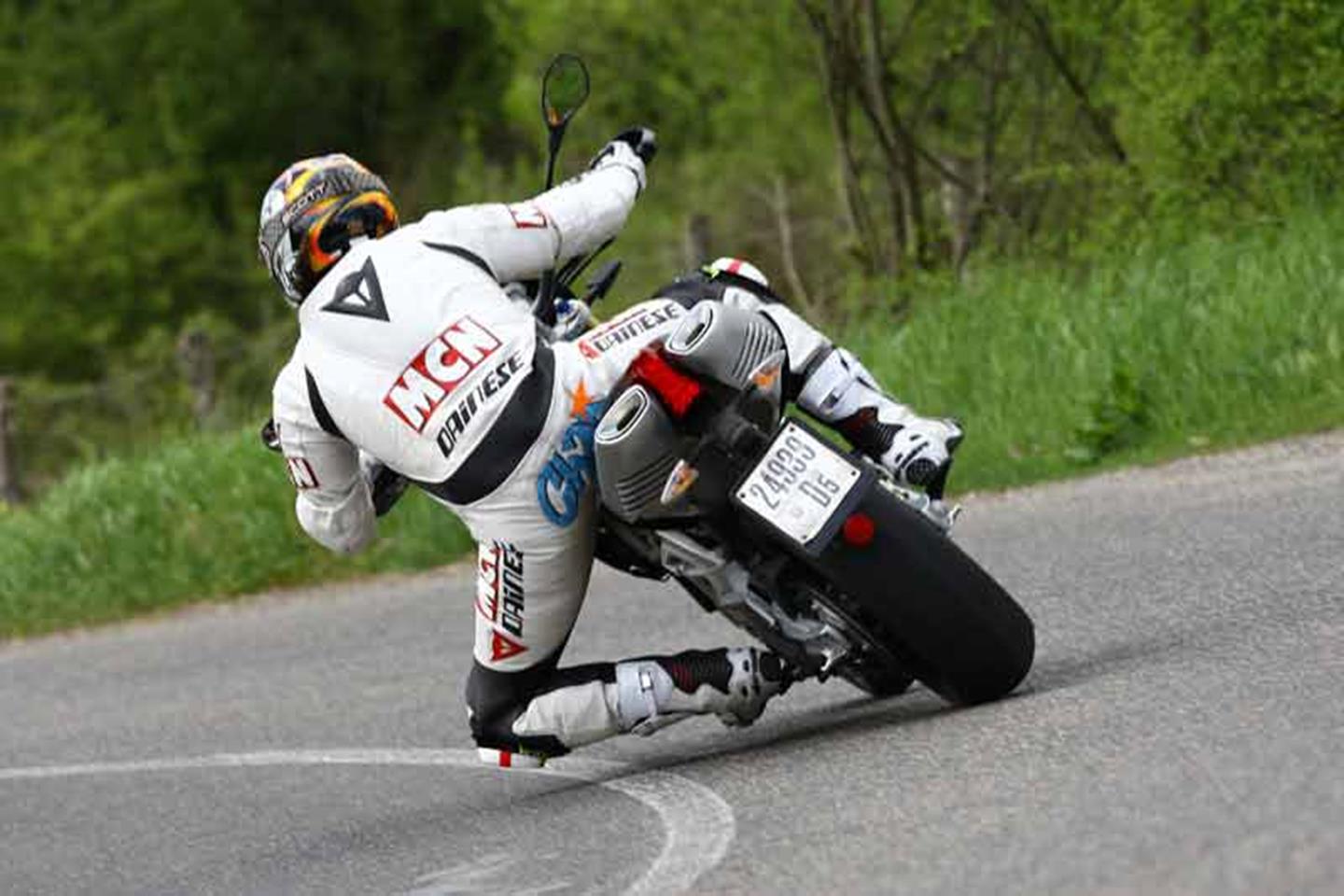 Aprilia Dorsoduro 750 conduce rápido a la vuelta de la esquina, con las rodillas casi bajas Aprilia Dorsoduro 750 conduce rápido a la vuelta de la esquina, con las rodillas casi bajas