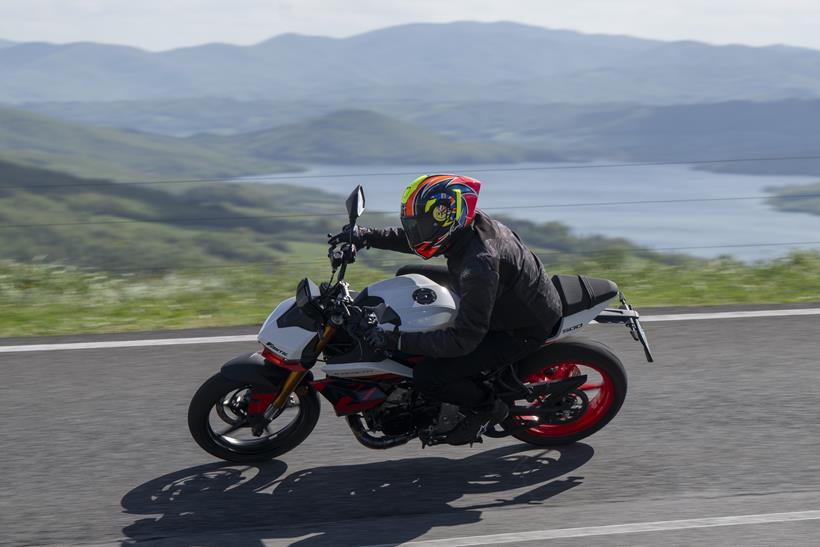 2026-on Fantic Stealth 500, leaning around a turn with a lake in the distance
