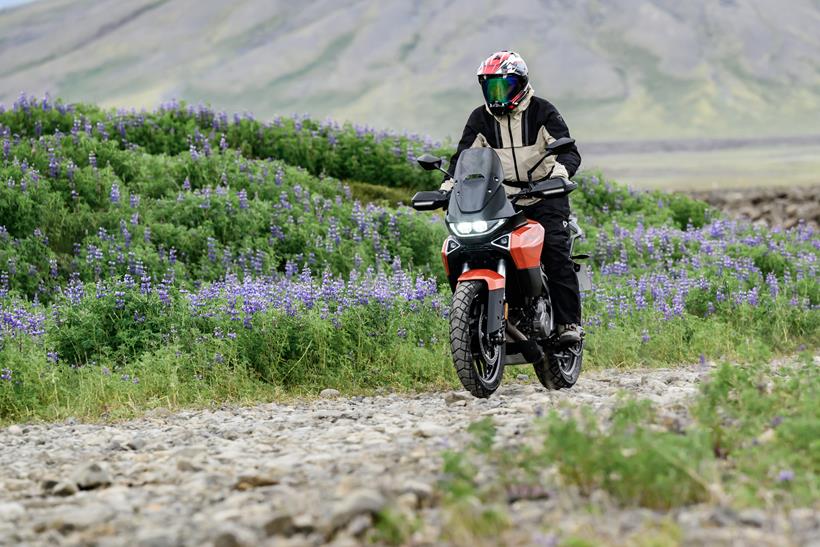 2027-on Norton Atlas Apex off-road through a flowery field